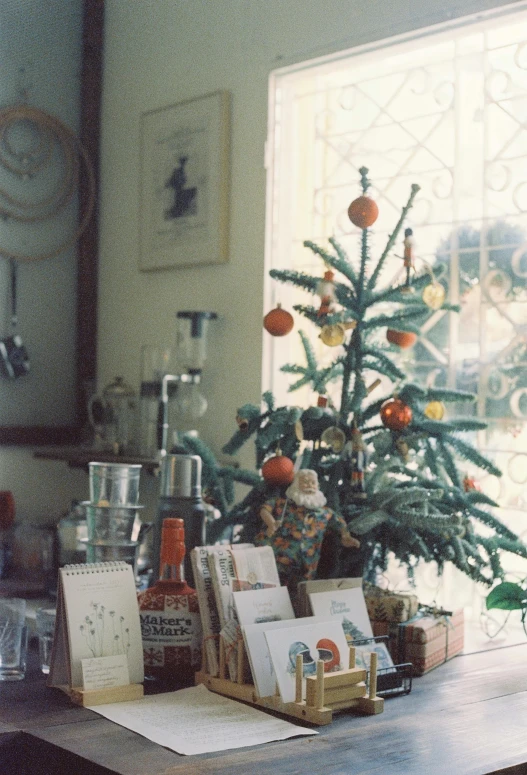 small christmas tree displayed with greeting cards in front of window