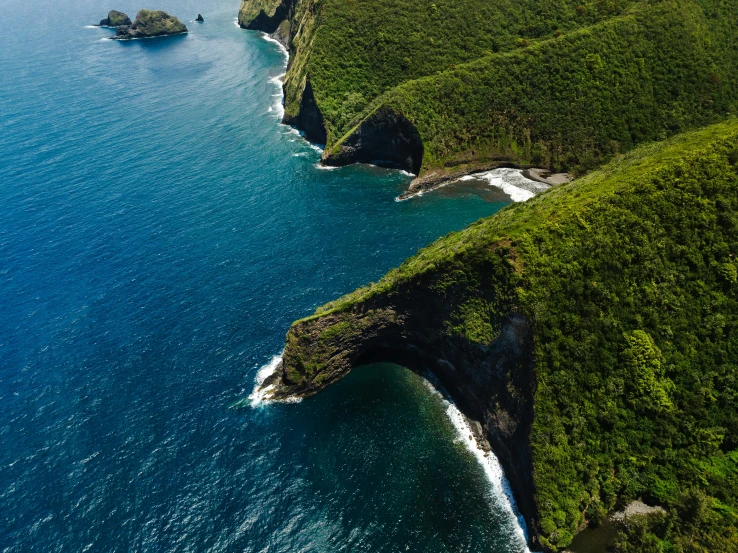 a cliff out on the side of a hill overlooking a blue ocean