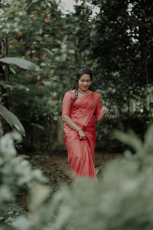 an indian woman in red standing in a forest