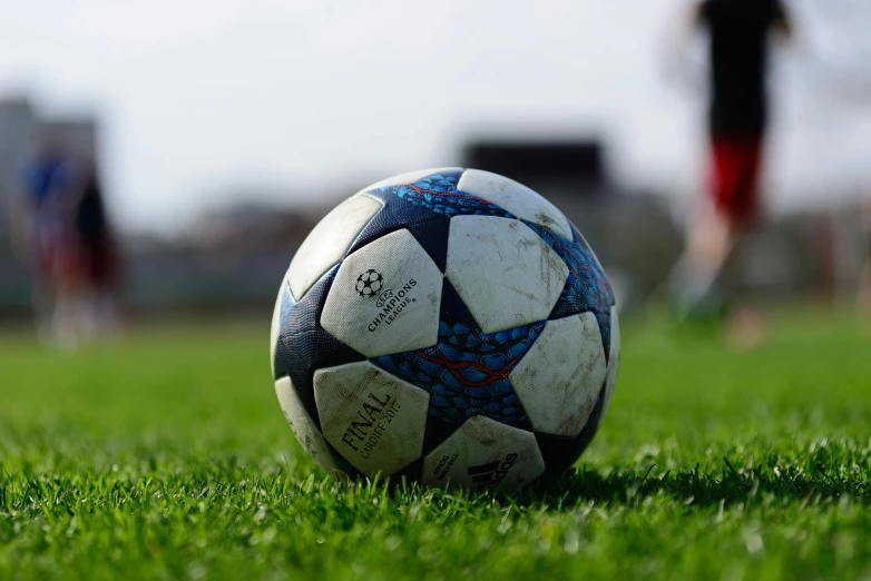 a soccer ball on a grass field with someone walking by