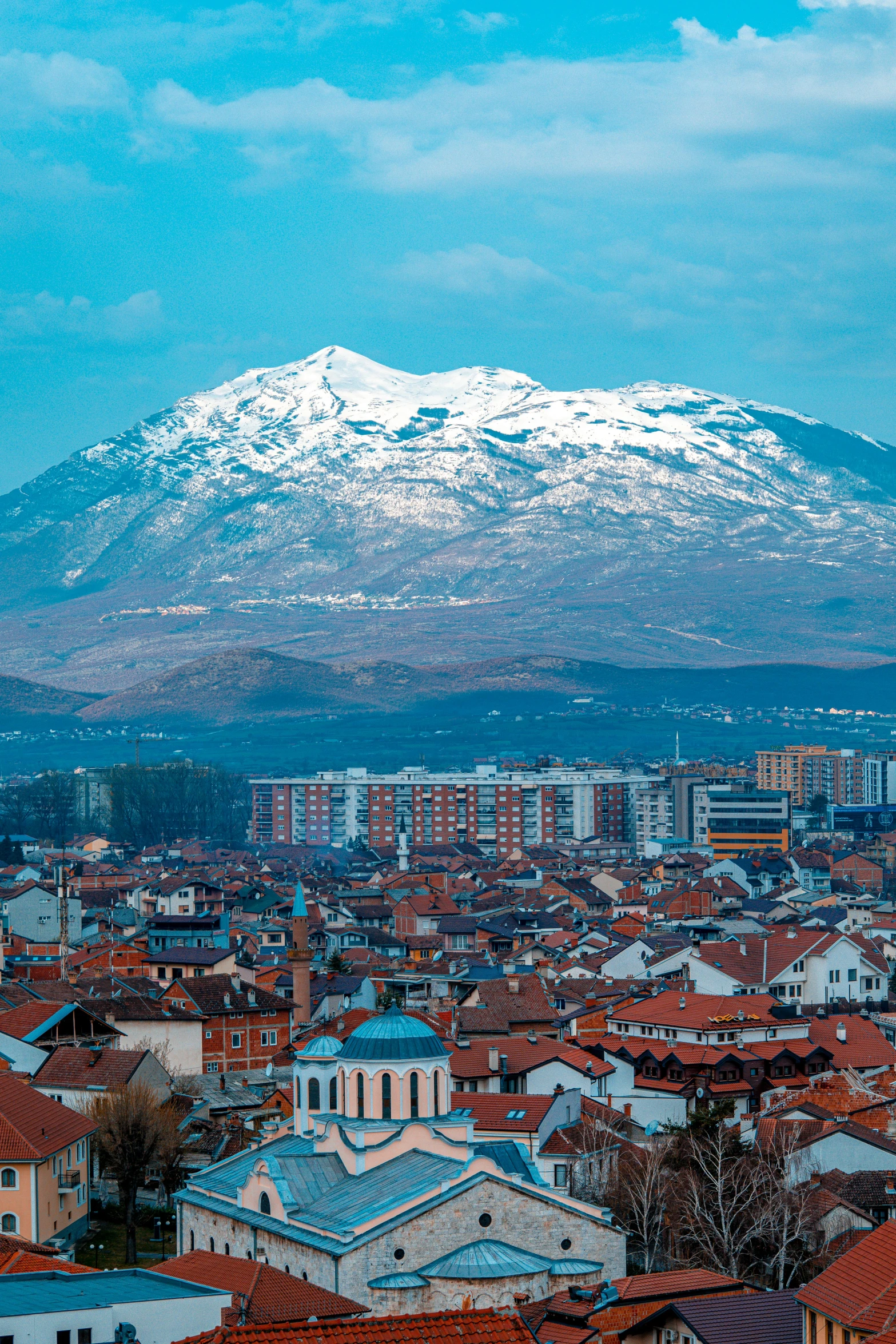 snow - capped mountain overlooks a city with rooftops