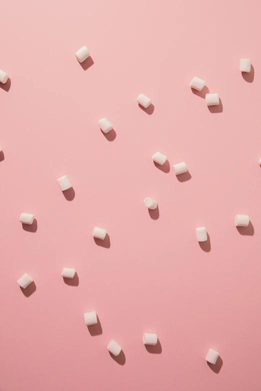 scattered sugar cubes on pink surface, showing an unusual shape
