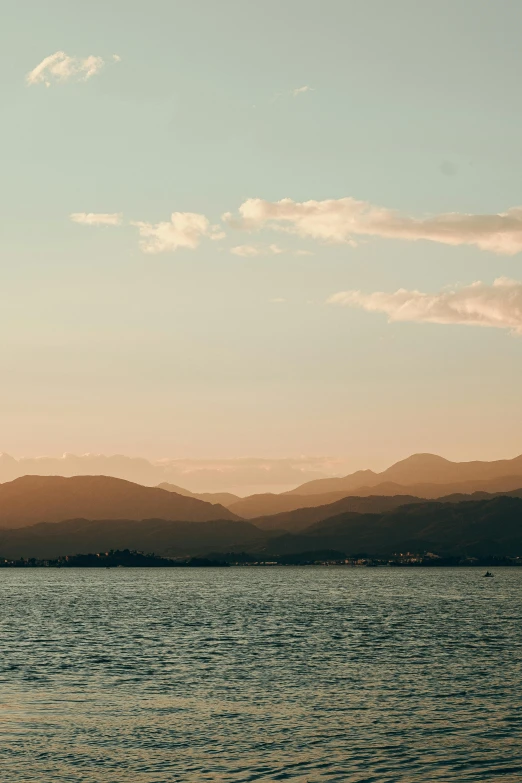 the sun is rising over the mountains near water