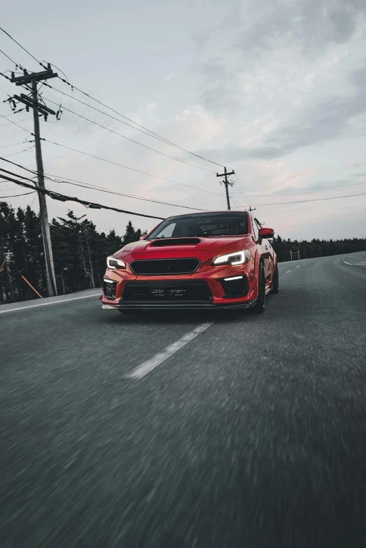 the red sports car is driving along the road