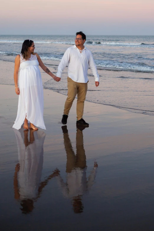 a man and woman holding hands walking on the beach