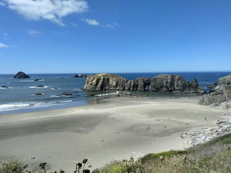 people are on the beach next to a rocky outcrop