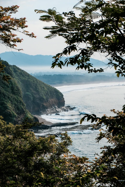 a mountain area is pictured in the distance as the ocean waves wash