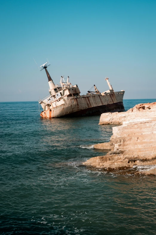 two boats sitting in the water with cliffs in the background