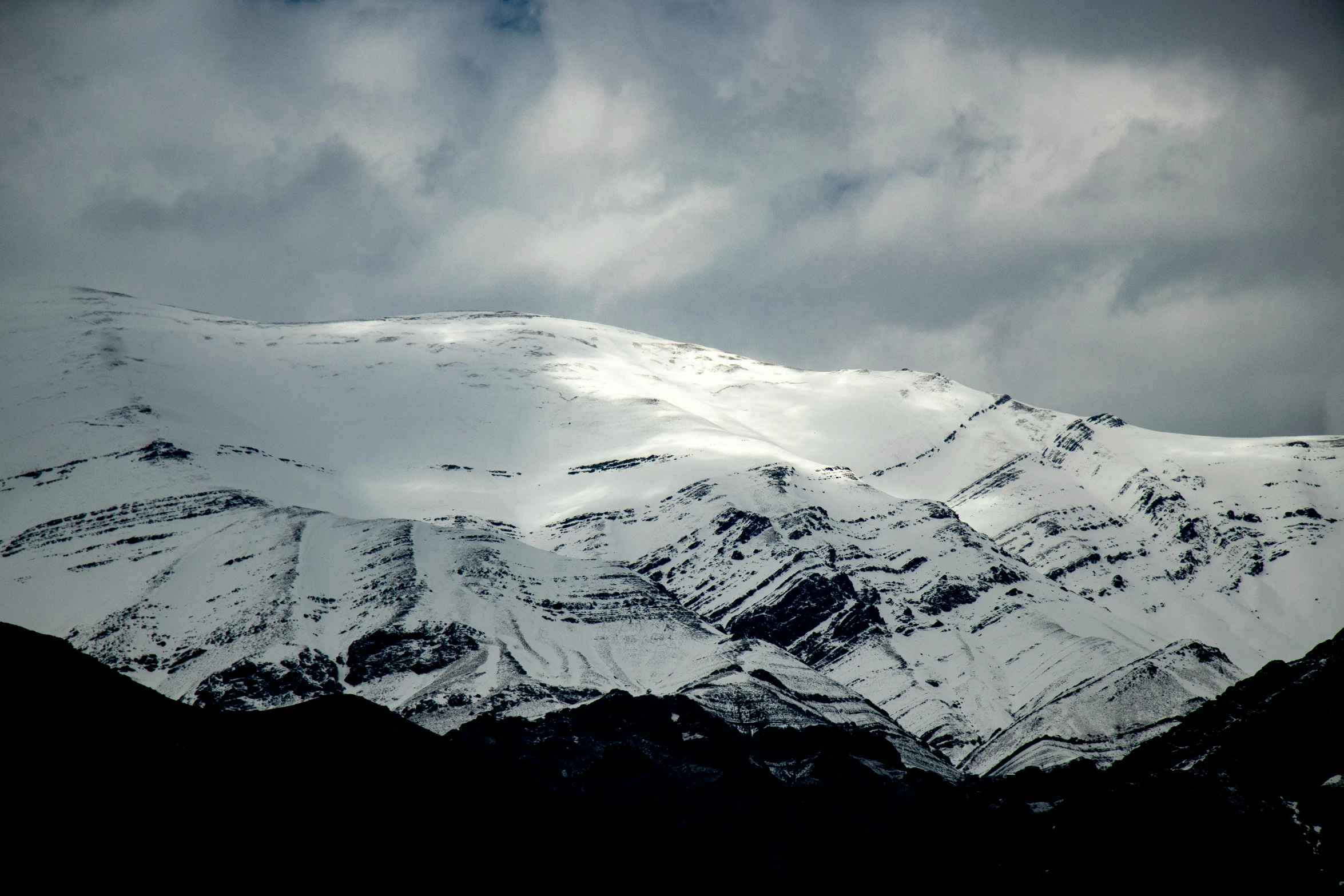 a snowy mountain is seen against a cloudy sky