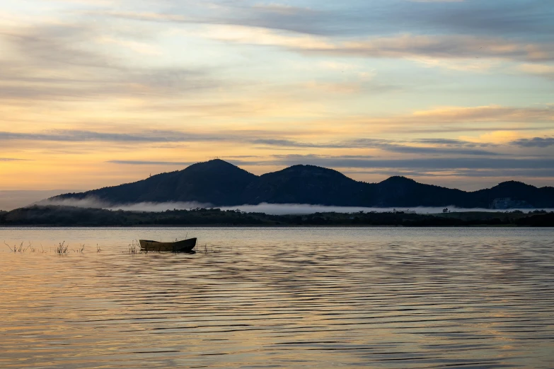 a boat is floating in the water with mountain in background