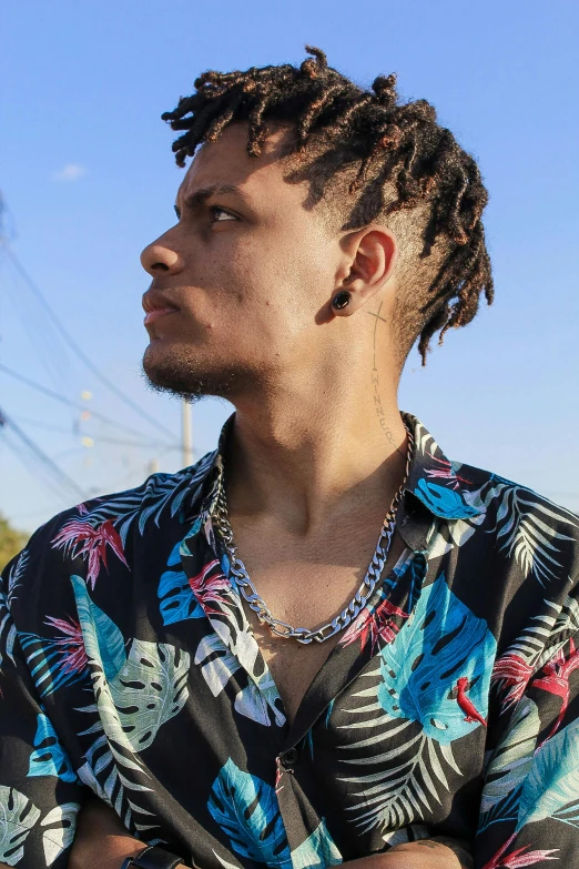 a man with dreadlocks wearing an floral shirt