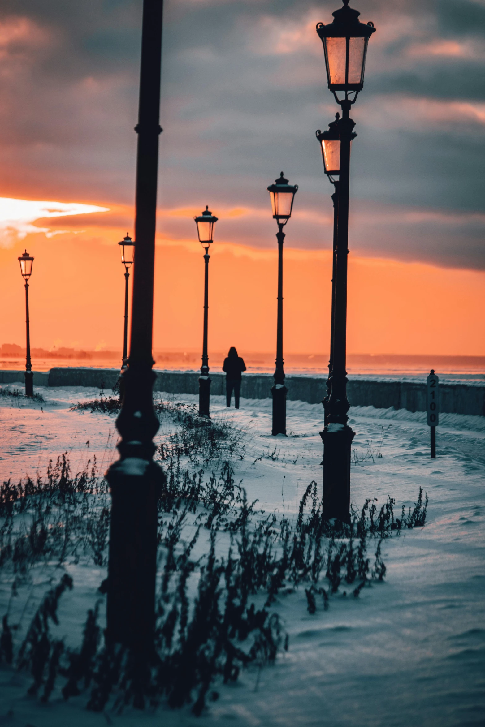 a couple walking down a snow covered path at dusk