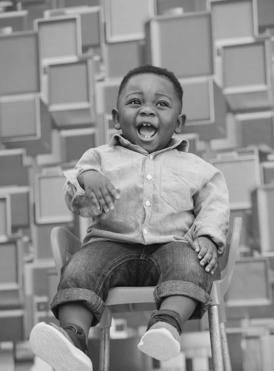 a little boy sitting on top of a wooden chair