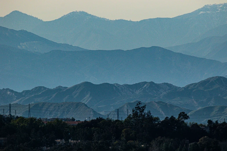 the mountains are covered with trees and dark blue haze