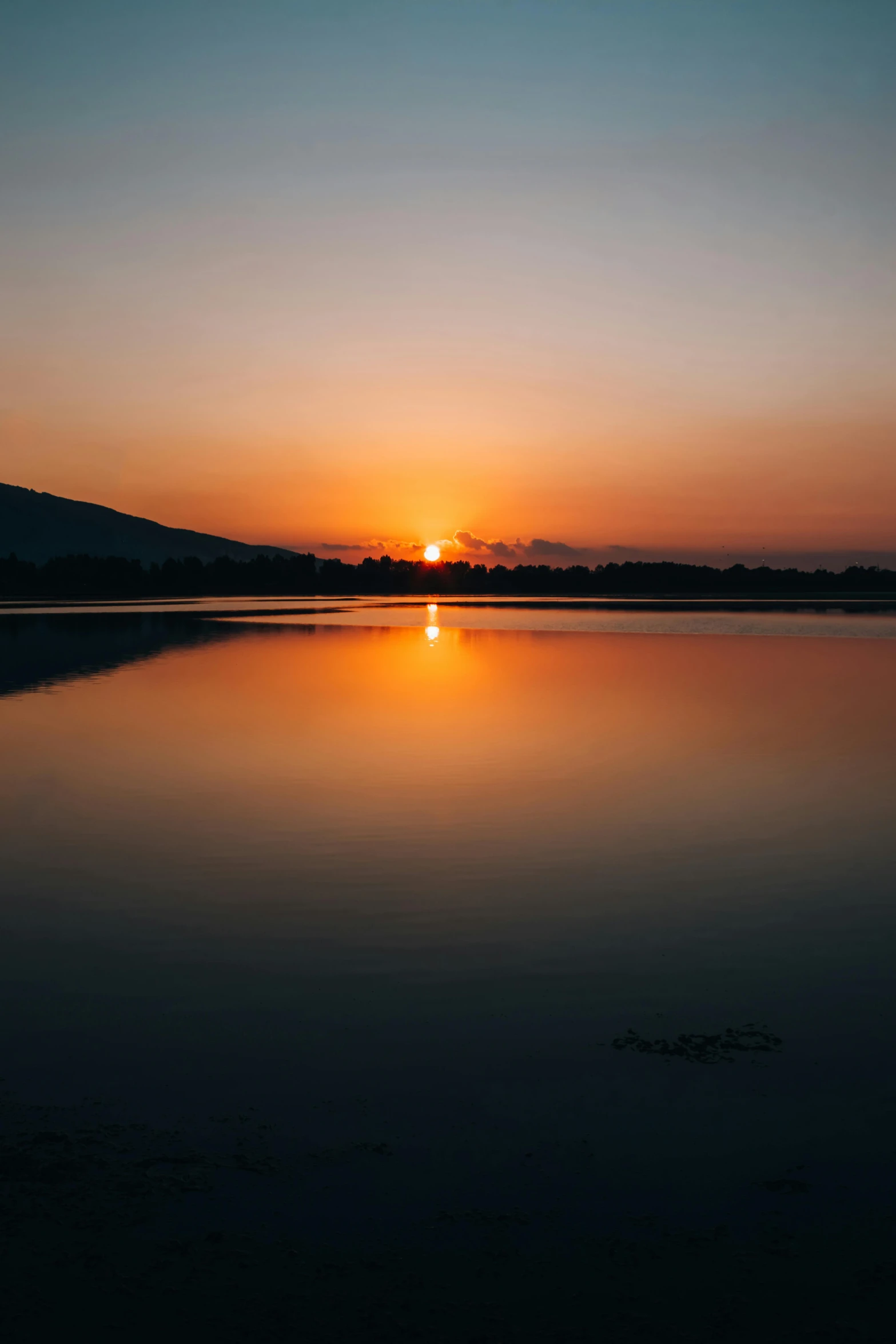 the sun rising over the horizon and reflected in the water