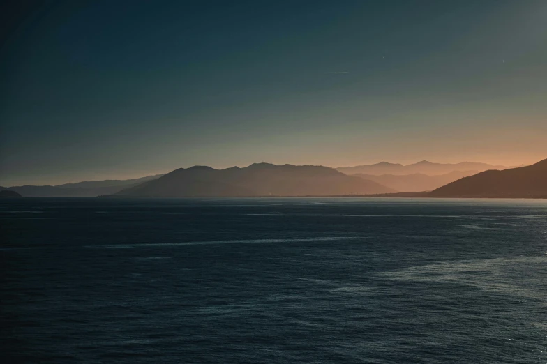 the sun is setting on a hill over a body of water