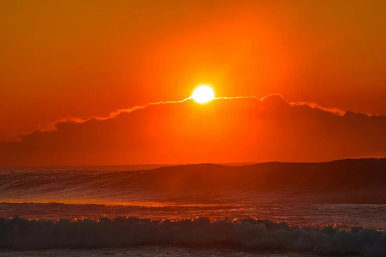 the sun setting over the ocean with waves