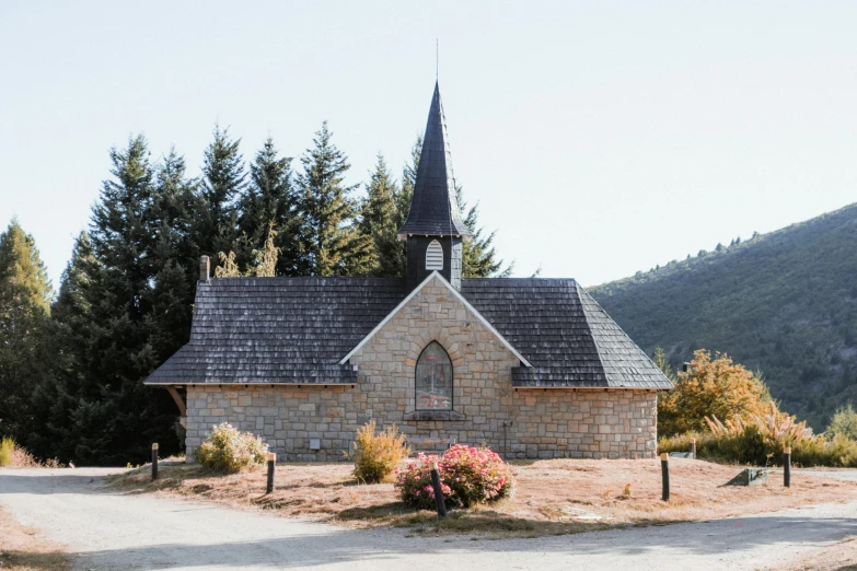 a stone church stands with trees on both sides