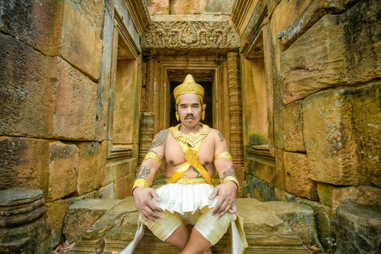 a young man in an elaborately designed headdress sits on a stone staircase