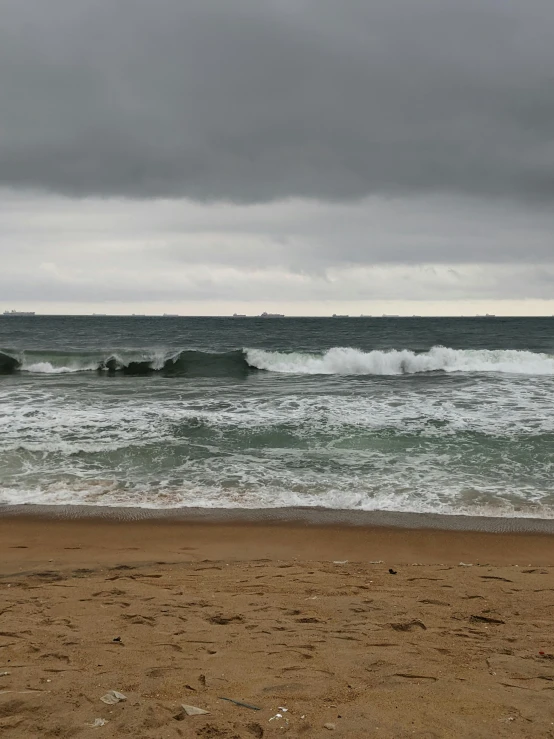 a person walking on the beach holding a surfboard