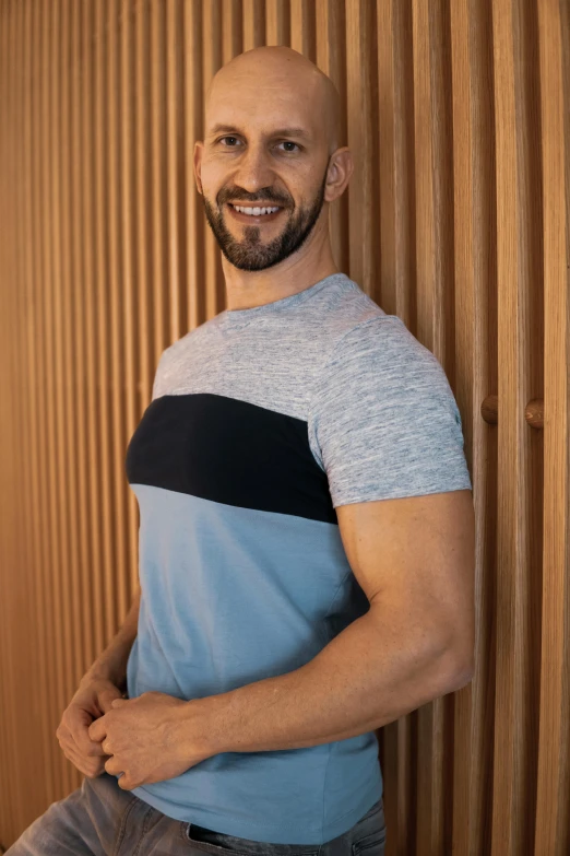 a man wearing jeans and a blue shirt smiles as he poses for the camera