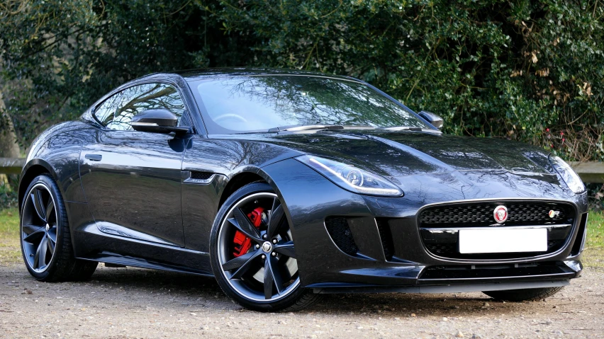 the dark grey sports car sits on a gravel road