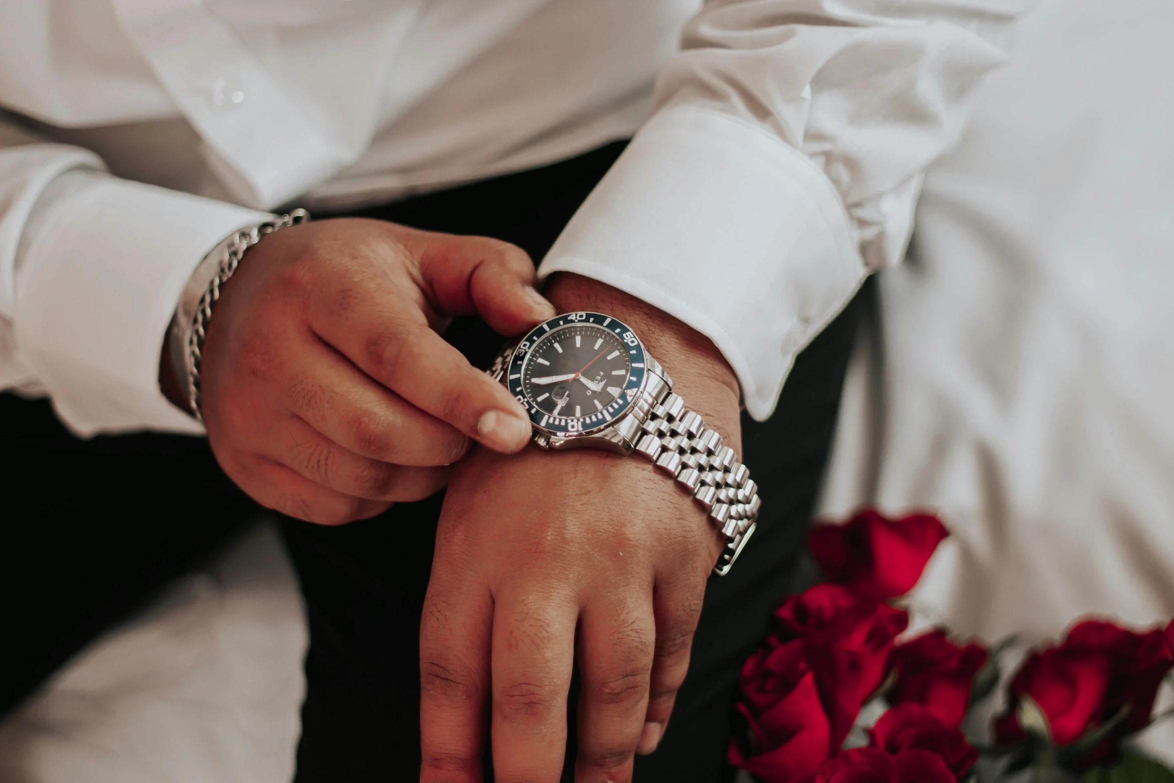 a man is showing his wedding watch with a bunch of roses