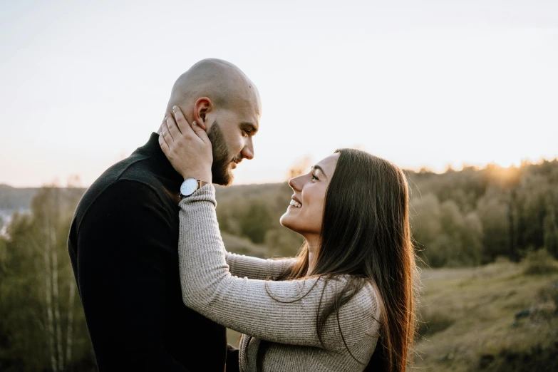 a beautiful couple standing close together and holding each other in a field