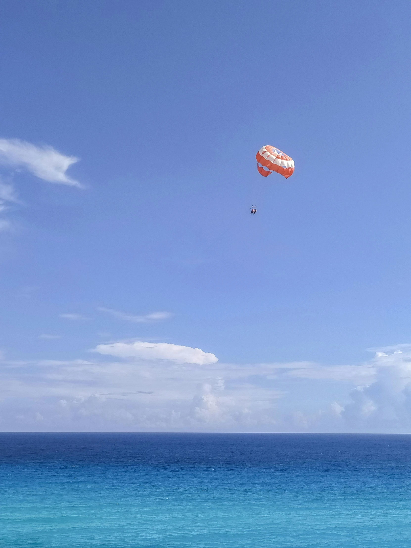 a person is flying a parachute over the blue water