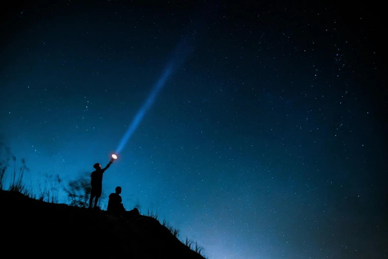 a man holding up a light on the night sky