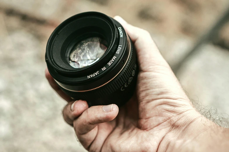 a hand holding a lens in front of it's mouth