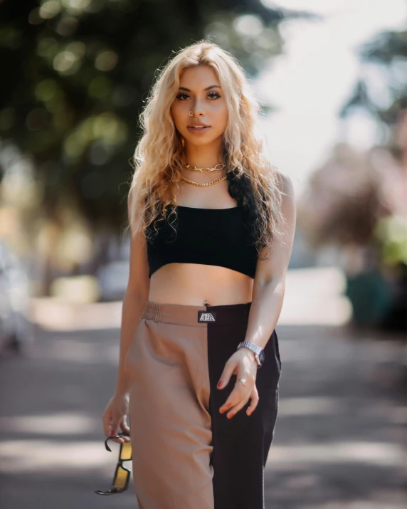 a woman is wearing a crop top and brown pants