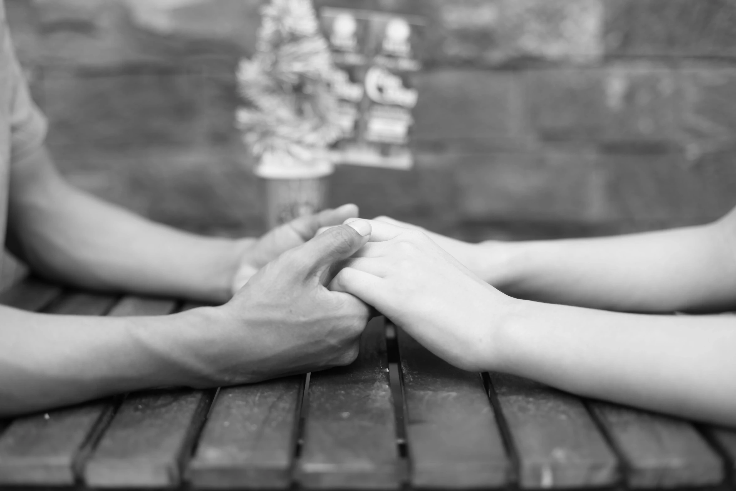 two people are holding hands on a wooden table
