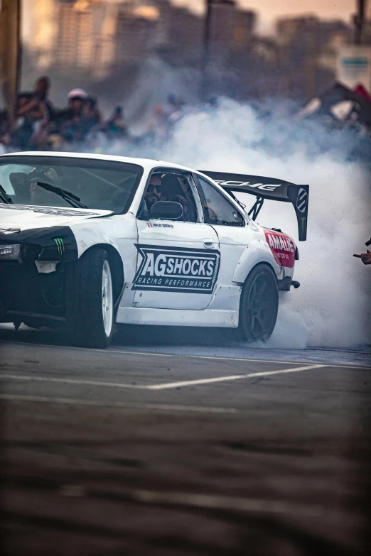 a white drift car driving down the street on a race course