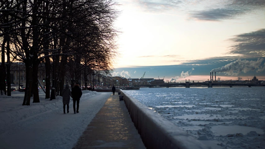 two people walking along a walkway on the snow covered ground