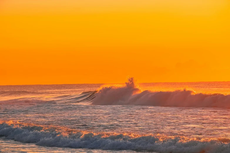 the sun is setting over the ocean as a surfer rides a wave