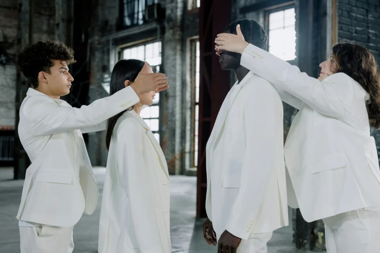 a man helping another woman put on white suit