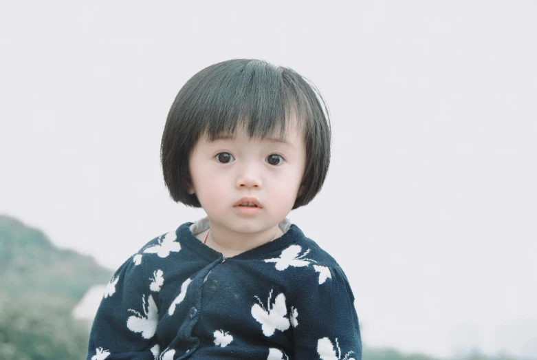 a baby girl with dark hair and wearing a shirt