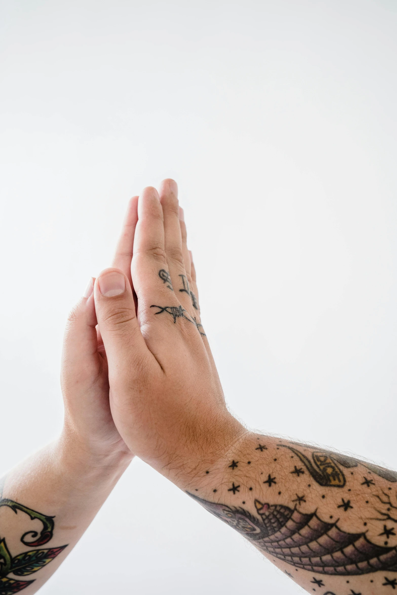 two hands holding each other with tattoos