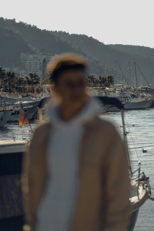 a man in white and black walking along water with boat