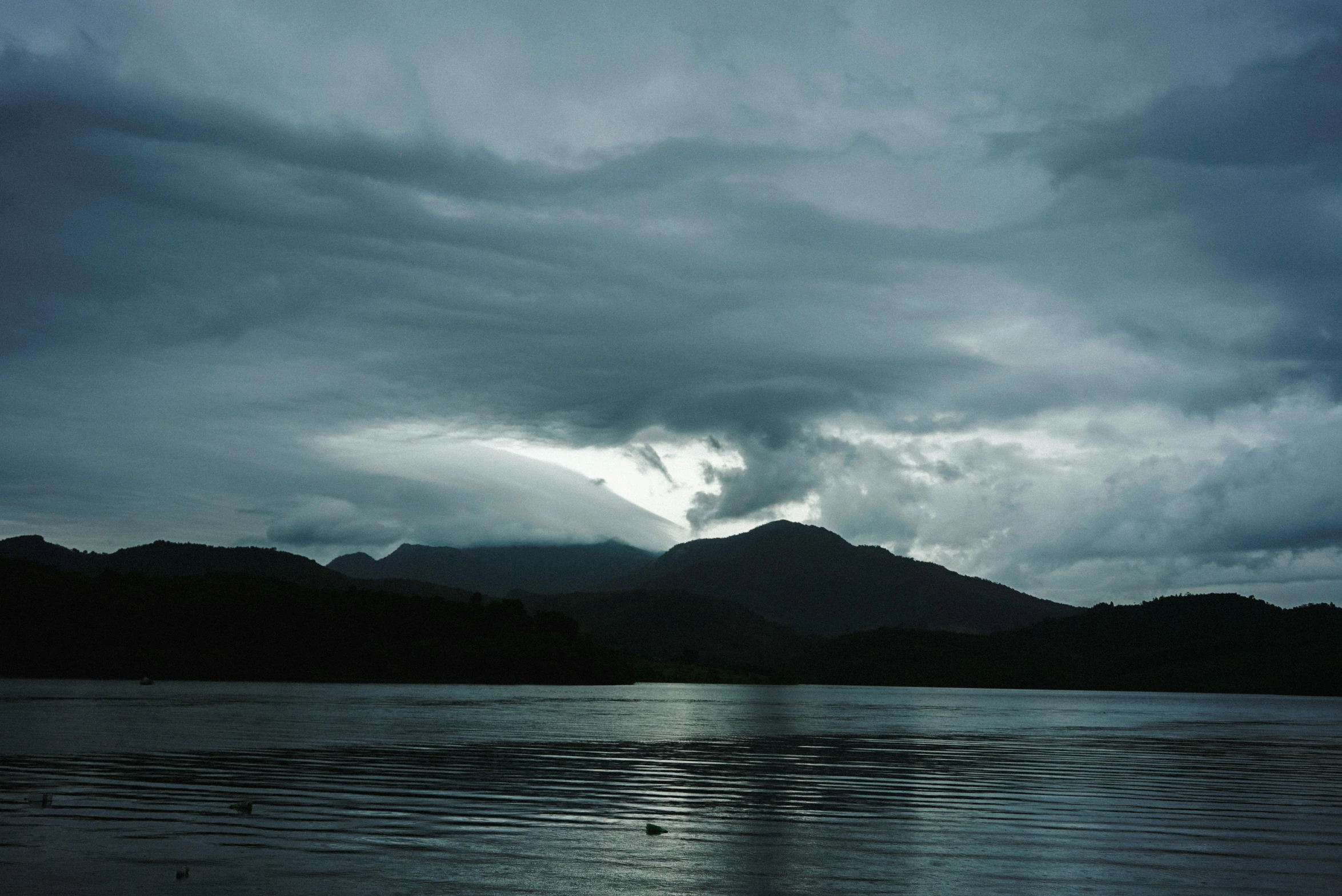 a lake and mountains under dark cloudy skies