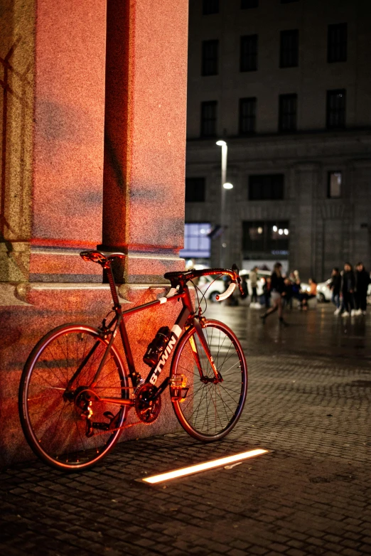 the bicycle is leaning against the column of an outside building