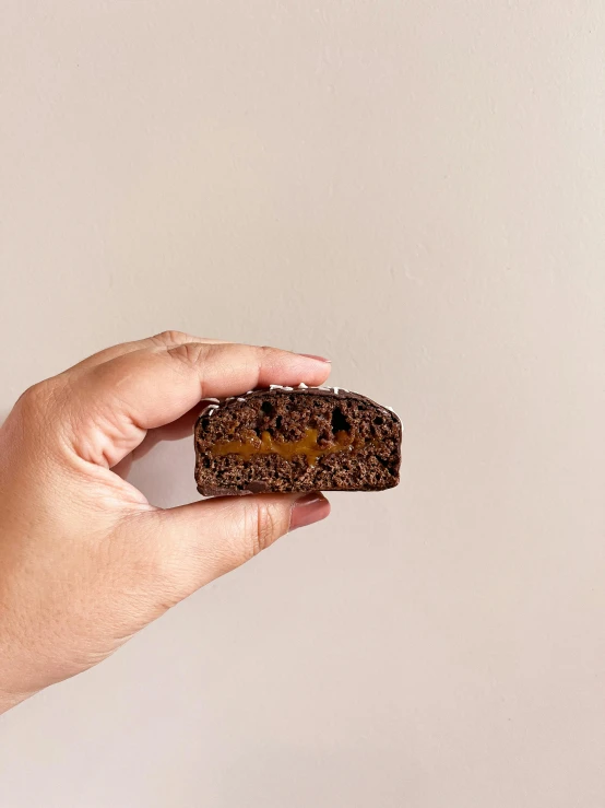 a hand is holding a piece of brownie