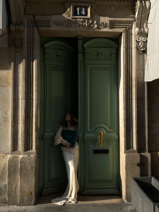 a woman is standing outside her door holding a book