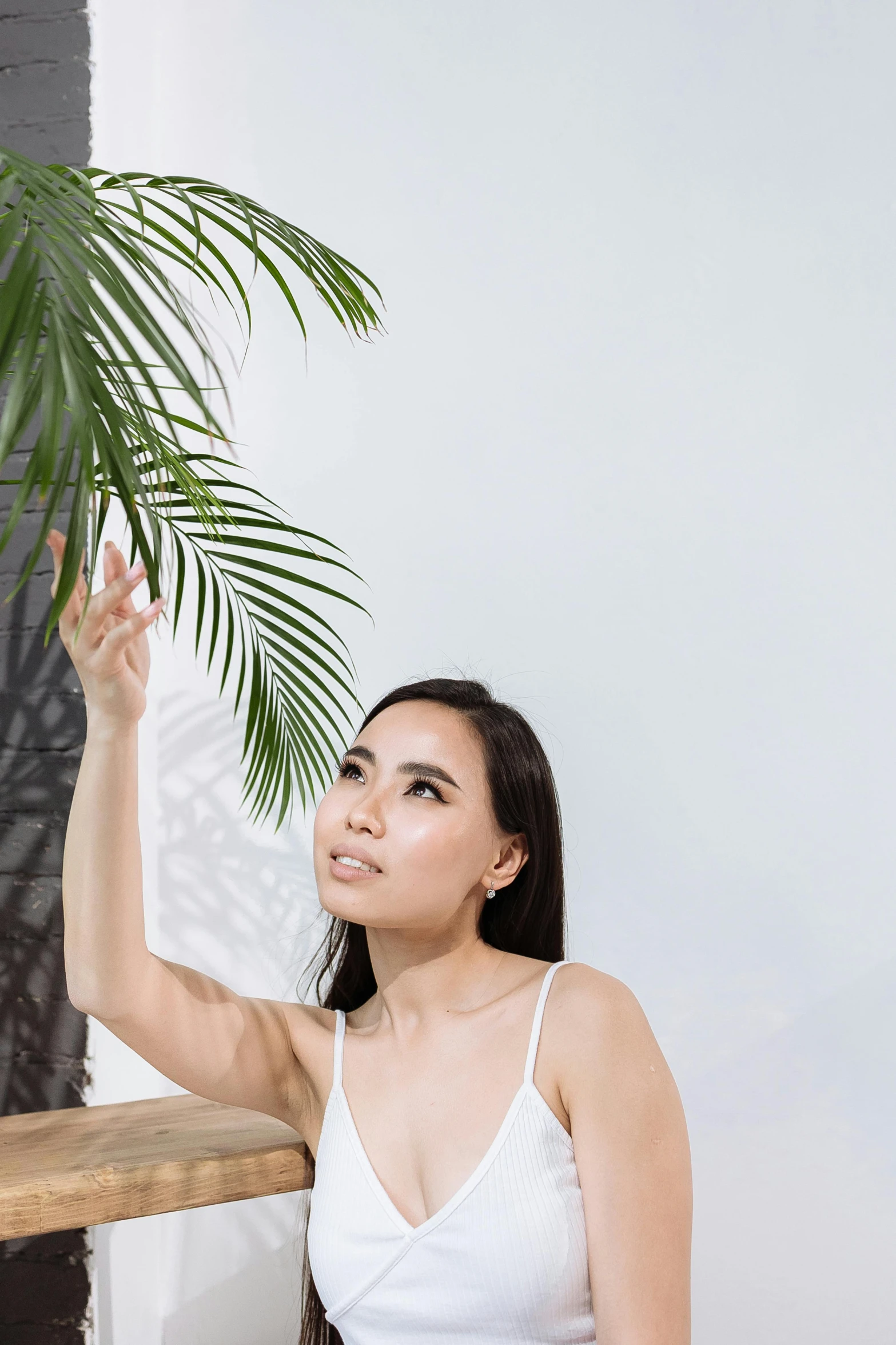 a beautiful woman holding up a leaf by the corner of a building