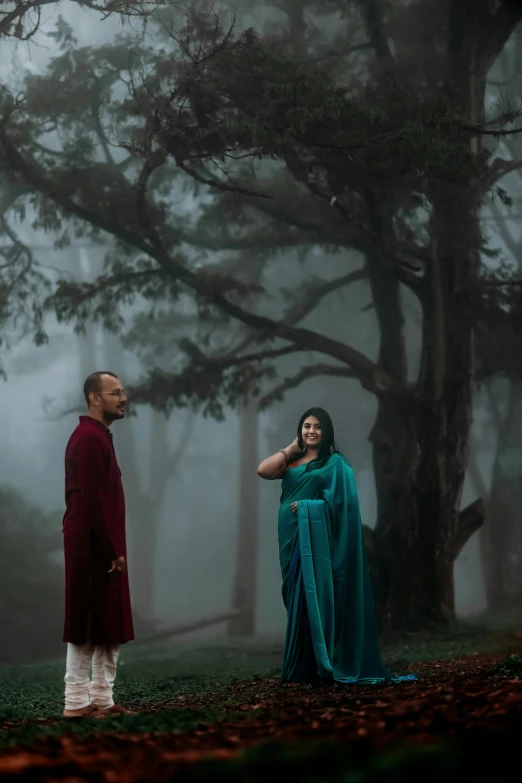 two people in colorful attire standing under a tree