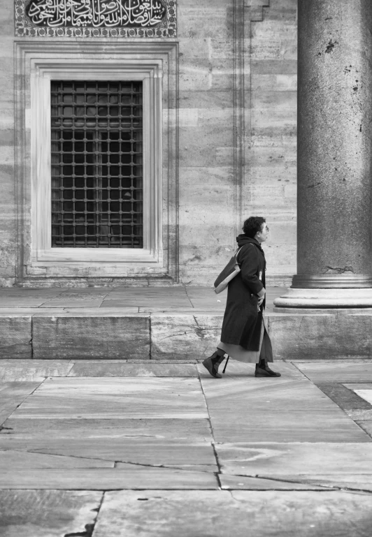 a woman walking past an old building with a glass front window