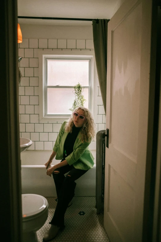 a woman sits in a doorway next to a sink and toilet