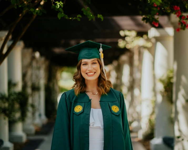 a female in a green graduation gown standing on a walkway