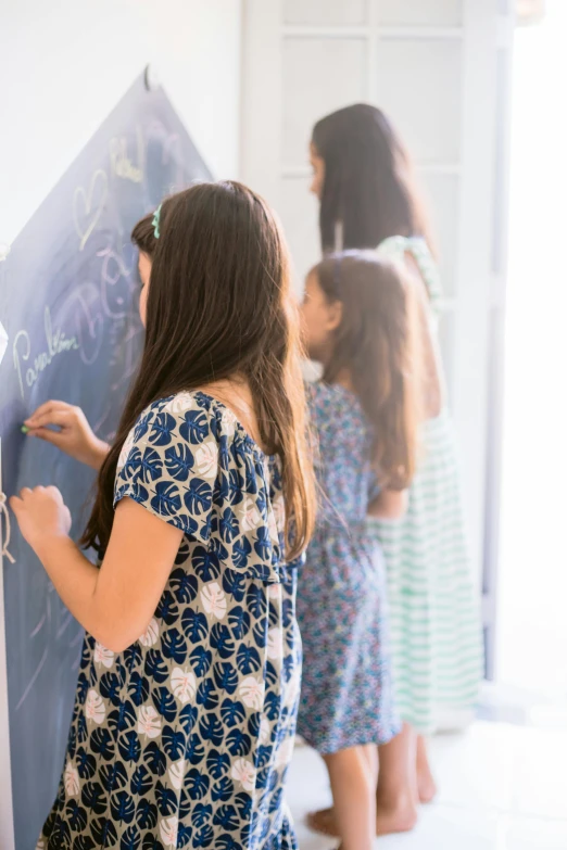 little girls drawing on a chalk board